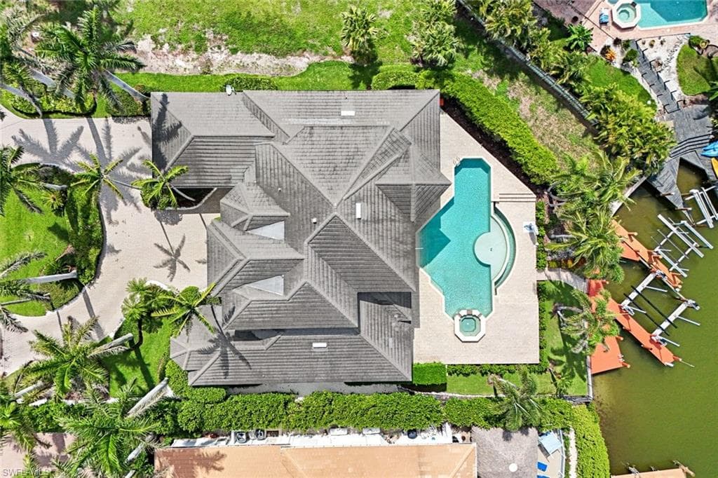 Drone / aerial view of a pool area with waterfront and dock with boat lift.