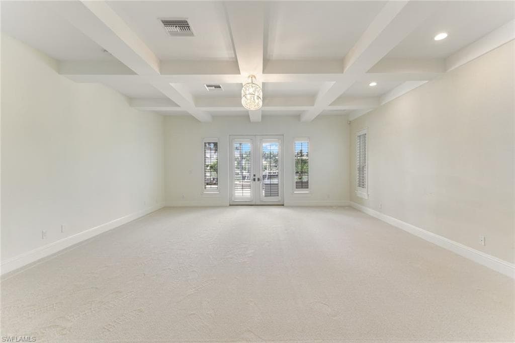 Downstairs Bedroom with beam ceiling, coffered ceiling, recessed lighting, french doors opening to pool area, with new lush carpeting. Extra large with ample natural light.