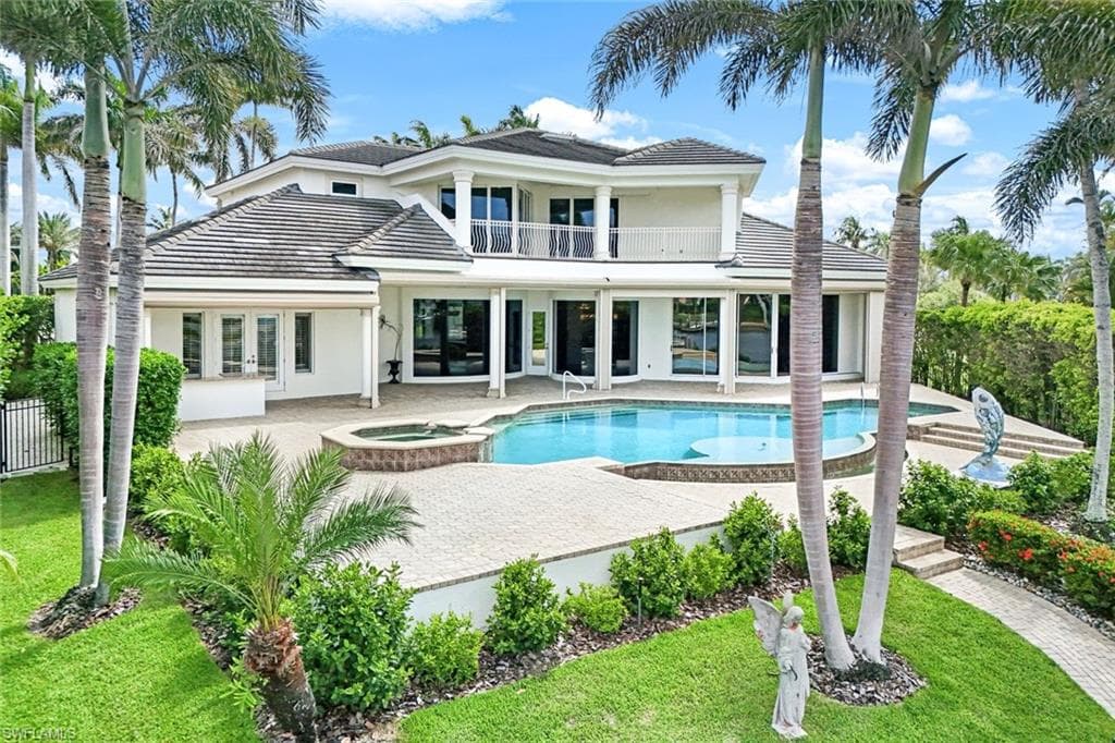 Rear view of house with a balcony, a patio, stucco siding, and a tiled roof. Lovely custom landscaping with beautiful fenced in yard.