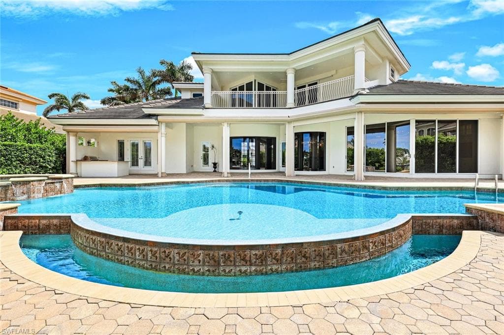 Back of property with a balcony, french doors, a pool with connected hot tub, fountain, patio area, and stucco siding. massive sun deck overlooking Compass Pass in Hurricane Harbor.