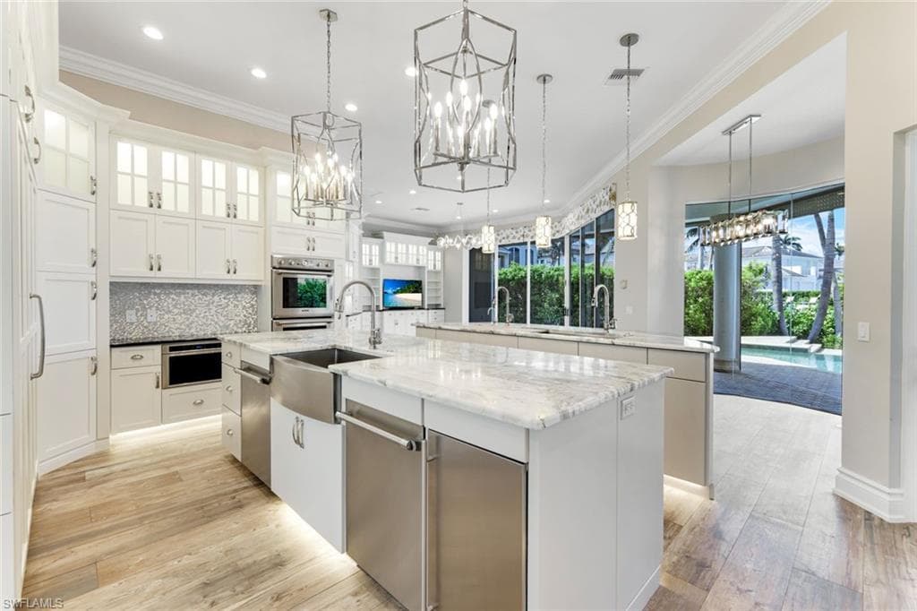 Kitchen with a chandelier, stainless steel appliances, a kitchen island with sink, plenty of natural light, and recessed lighting