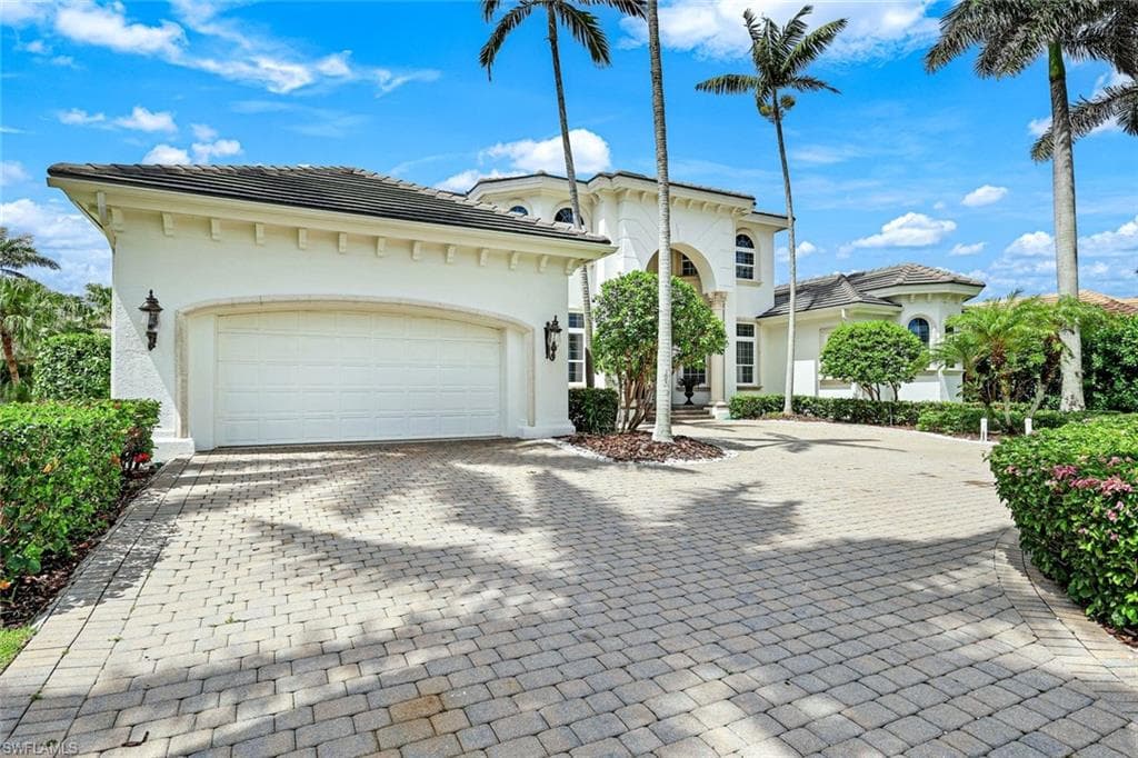 Mediterranean / spanish-style house featuring decorative driveway, stucco siding, 3 car. attached garage, and a newer cement tiled roof.