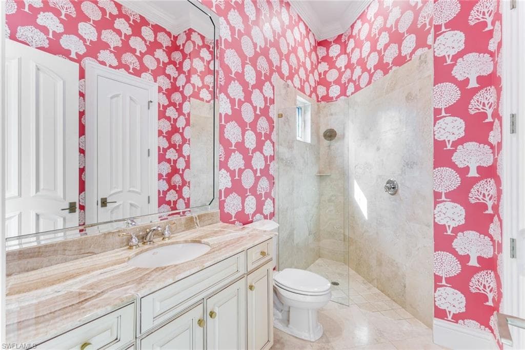 Ensuite full bathroom #2 with crown molding, vanity, a tile shower, and wallpapered walls