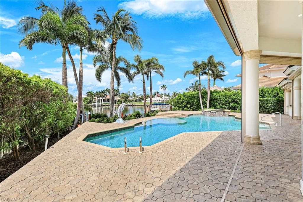 View of swimming pool with a patio area, a pool with connected hot tub, and a water view