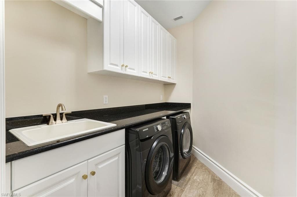 Laundry room featuring washing machine and clothes dryer, light wood-style floors, and cabinet space