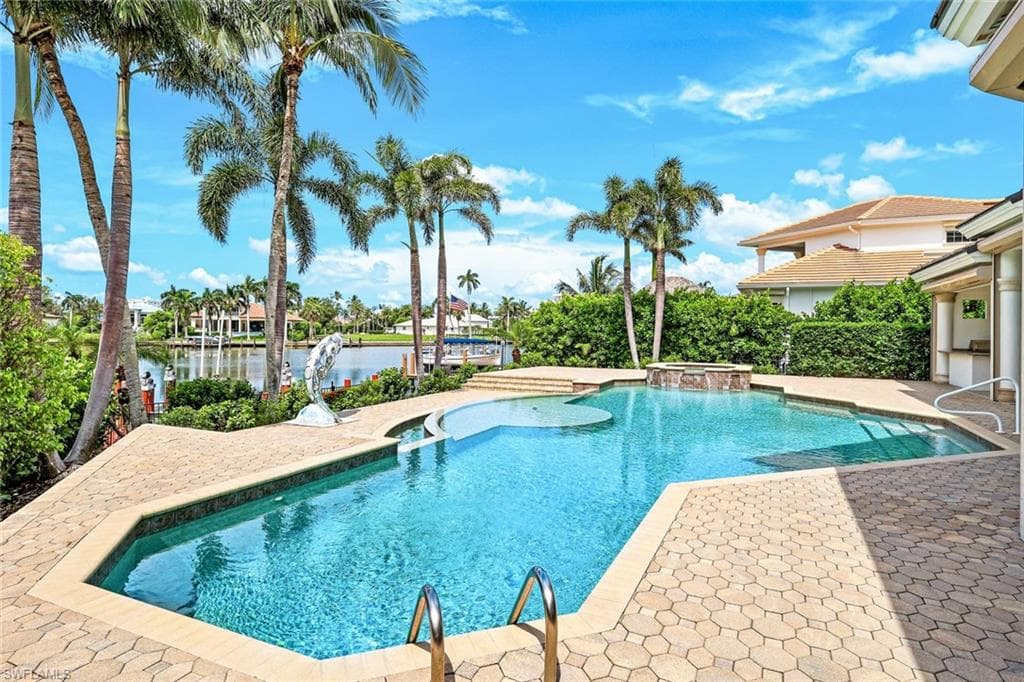 View of swimming pool featuring a patio, a pool with connected hot tub, and a water view