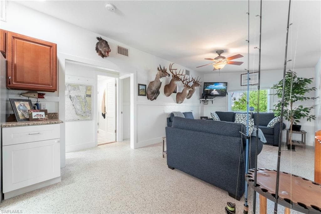 Living area with a ceiling fan and dark aggregate flooring