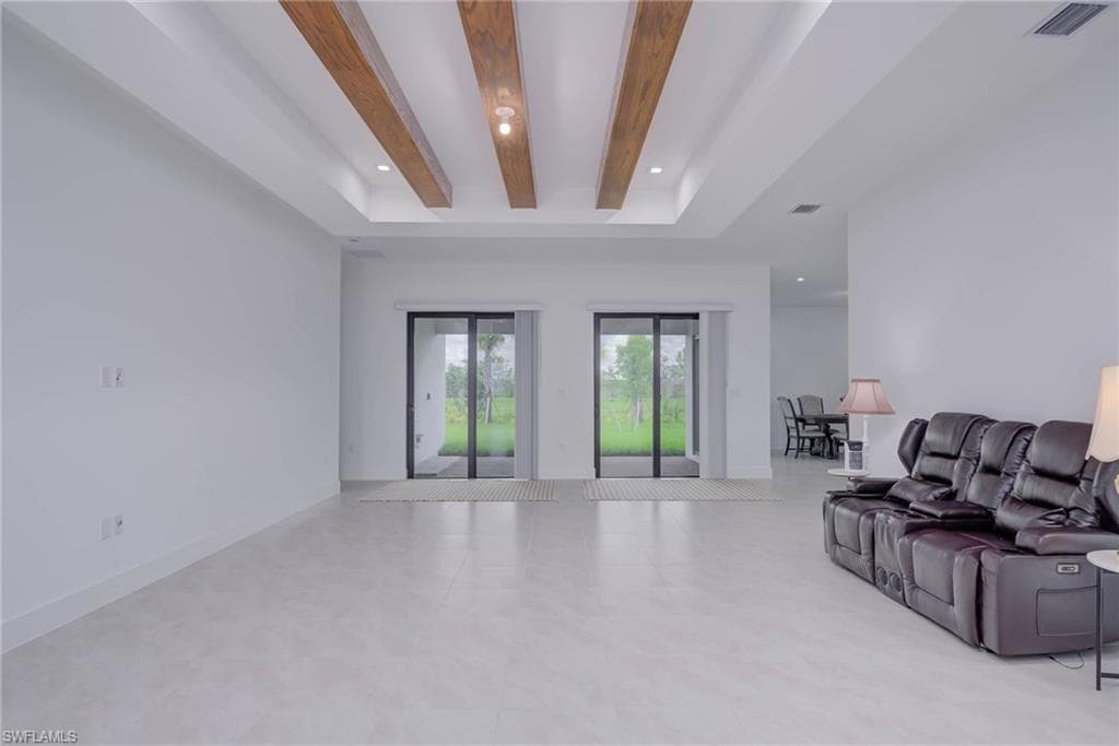 Living room with recessed lighting, tile patterned flooring, beam ceiling, and a raised ceiling