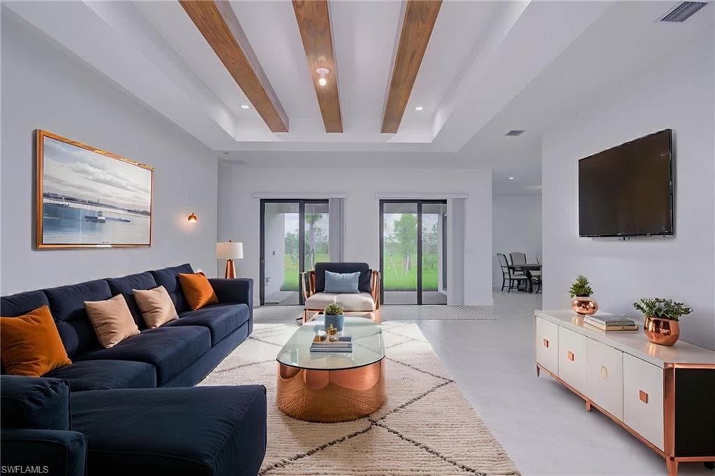 Living room featuring recessed lighting, finished concrete flooring, beamed ceiling, and a tray ceiling- digitally staged