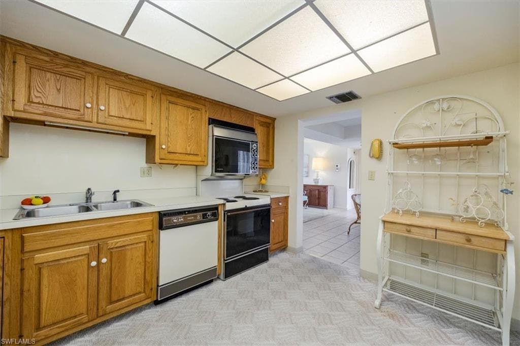 Kitchen featuring white appliances, brown cabinetry, and light countertops