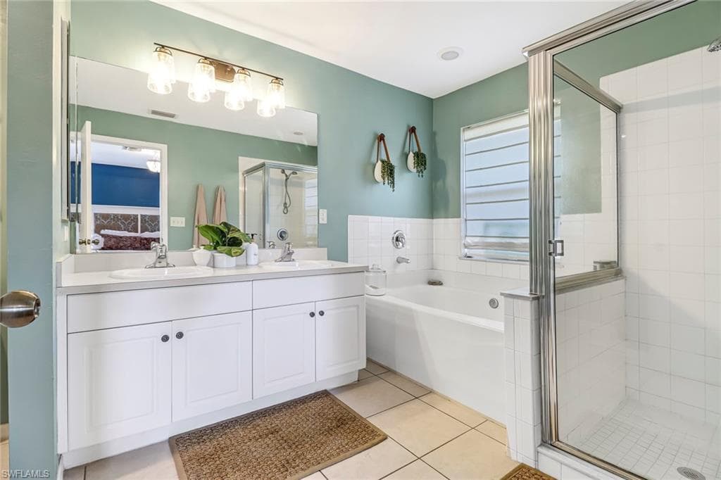 Full bathroom with a stall shower, a garden tub, double vanity, and tile patterned floors