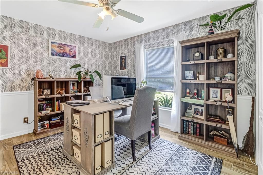 Office space featuring wallpapered walls, a ceiling fan, and light wood-style flooring