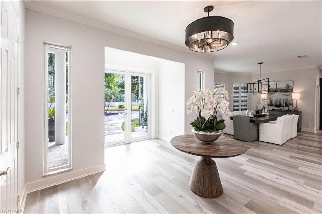 Entryway with ornamental molding, french doors, and light hardwood / wood-style flooring