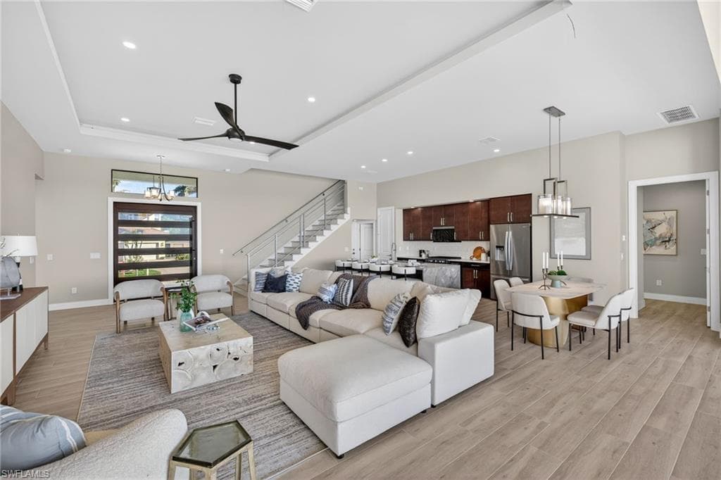 Living room featuring a chandelier, light wood finished floors, stairs, recessed lighting, and a ceiling fan