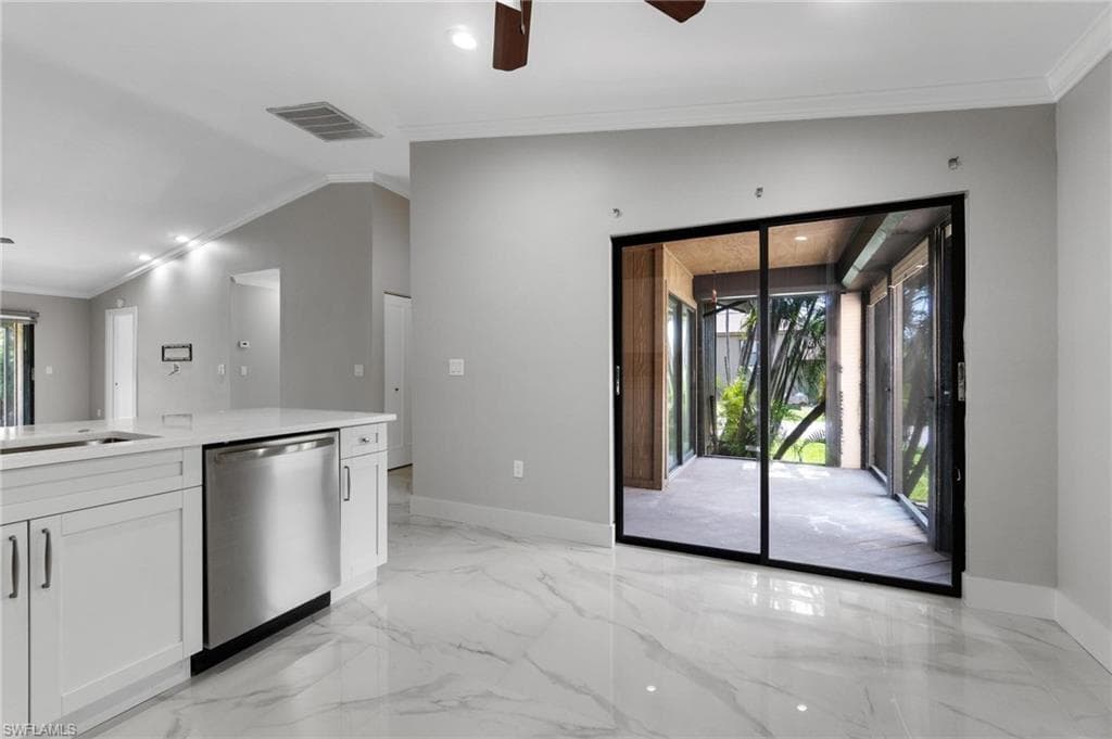 Kitchen with dishwasher, healthy amount of natural light, white cabinetry, a ceiling fan, and ornamental molding