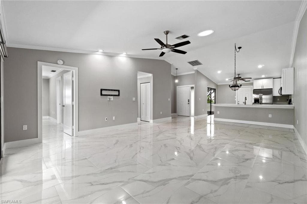 Unfurnished living room featuring a ceiling fan, light marble finish flooring, crown molding, recessed lighting, and lofted ceiling