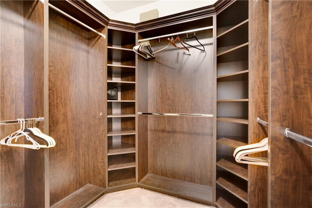 Walk in closet with builkt-in shelving and wall safe