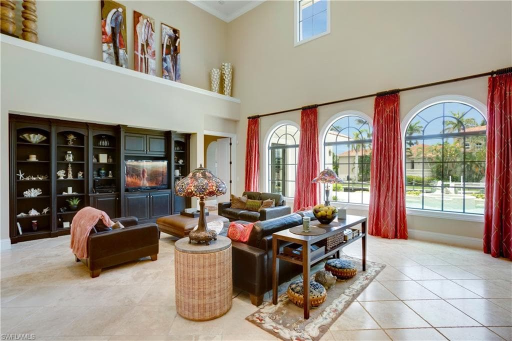 Living area with light tile patterned flooring, ornamental molding, and a towering ceiling