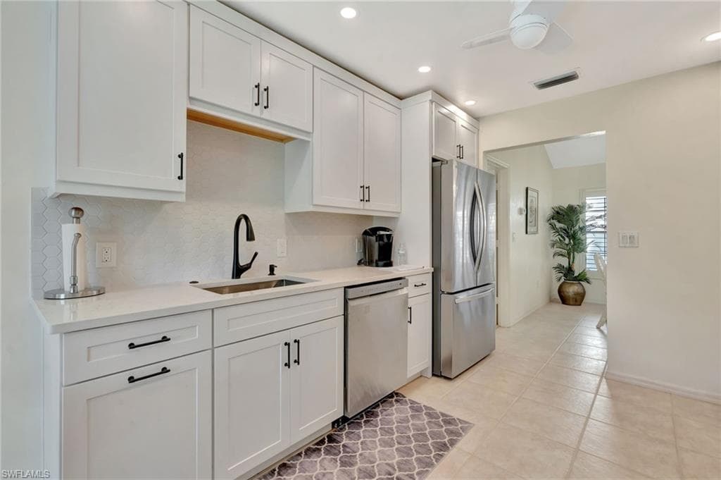 Kitchen featuring stainless steel appliances, decorative backsplash, light countertops, white cabinets, and recessed lighting