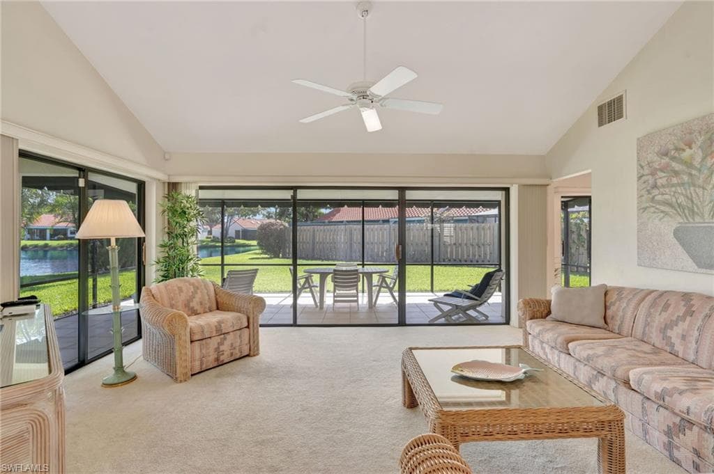 Carpeted living area featuring high vaulted ceiling, ceiling fan, plenty of natural light, and a water view