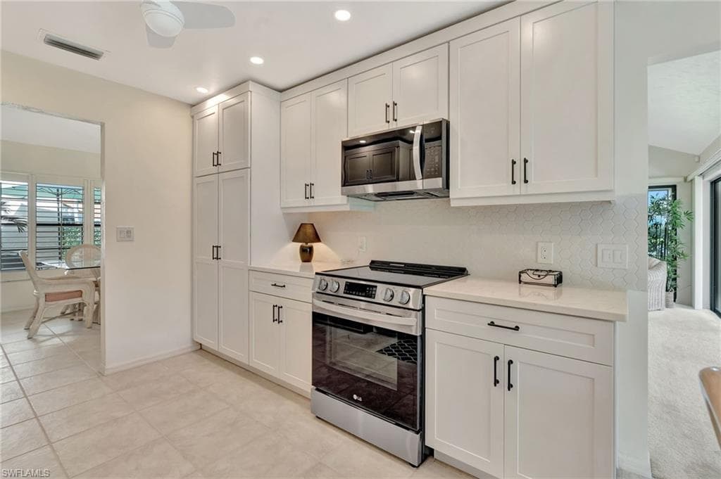Kitchen featuring appliances with stainless steel finishes, healthy amount of natural light, decorative backsplash, white cabinets, and recessed lighting