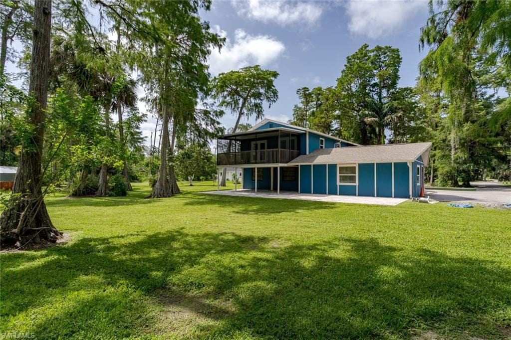 Rear view of house with a lawn and a balcony