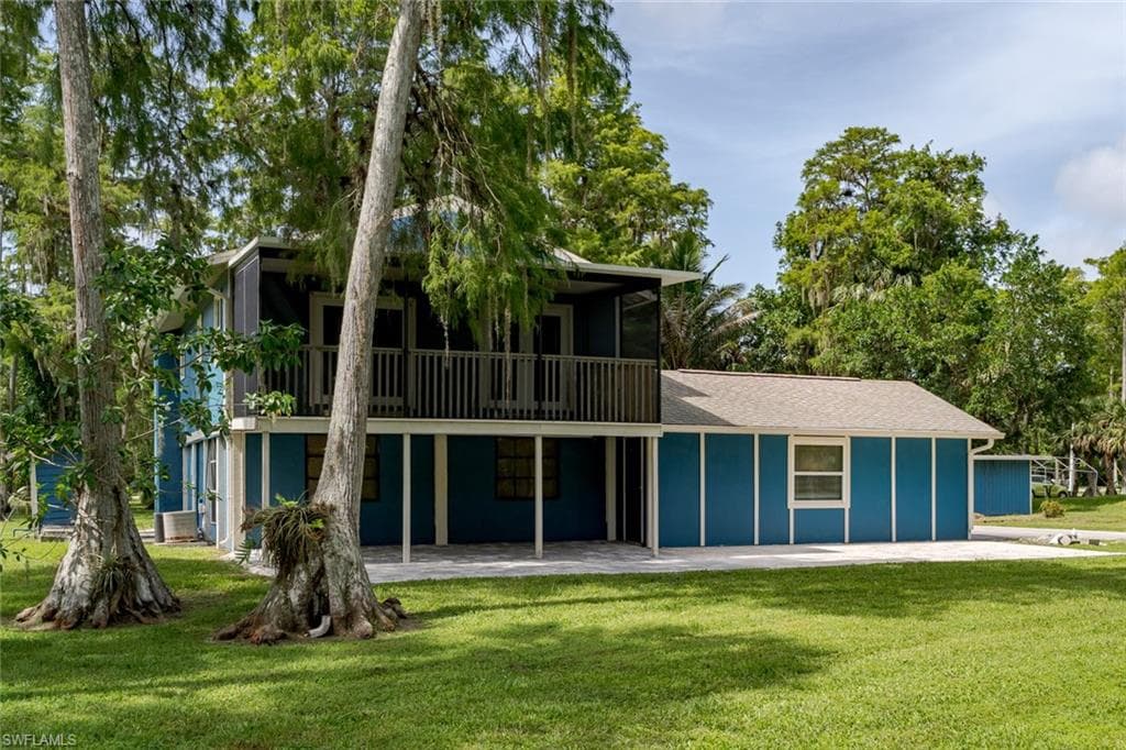 Back of house with a yard, a patio, and board and batten siding