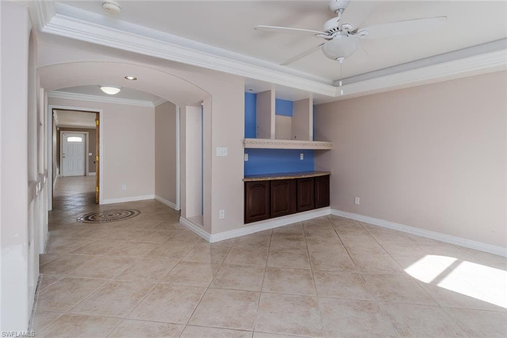 bedroom featuring arched walkways, crown molding, light tile patterned floors, a raised ceiling, and a smoke detector