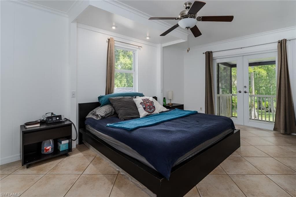 Bedroom featuring french doors, access to outside, ornamental molding, light tile patterned floors, and multiple windows