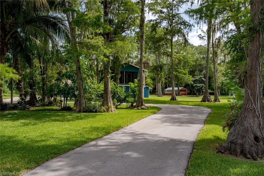 View of home's community with a yard and asphalt driveway