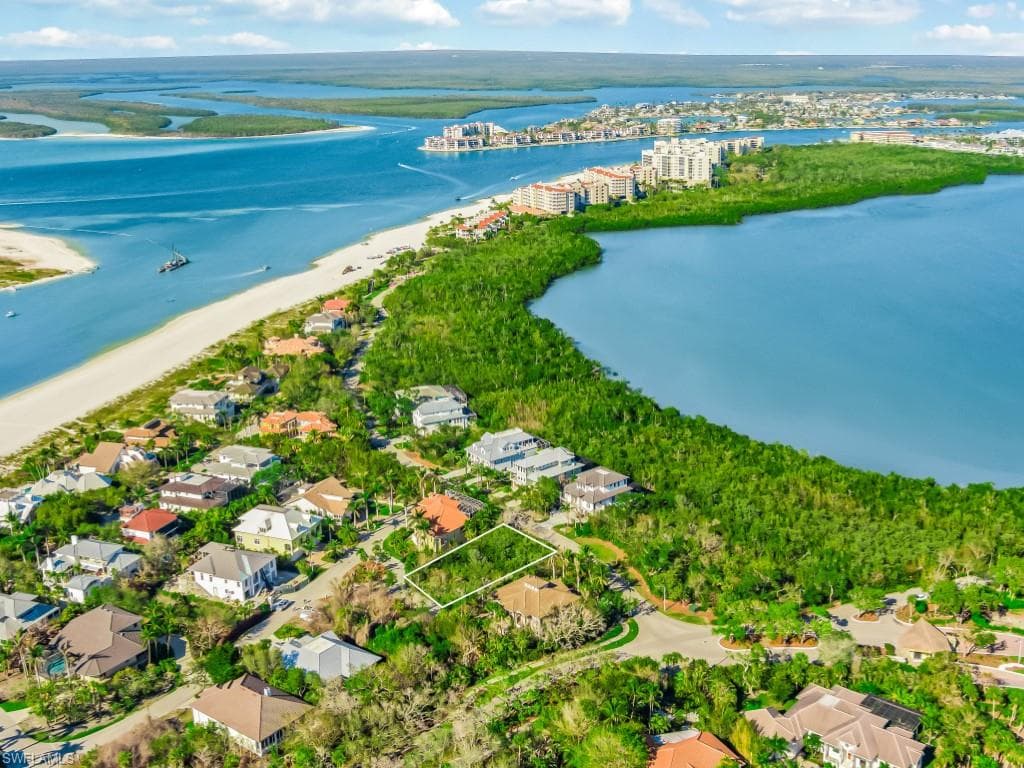 Aerial view of property and surrounding area featuring waterfront with a beach
