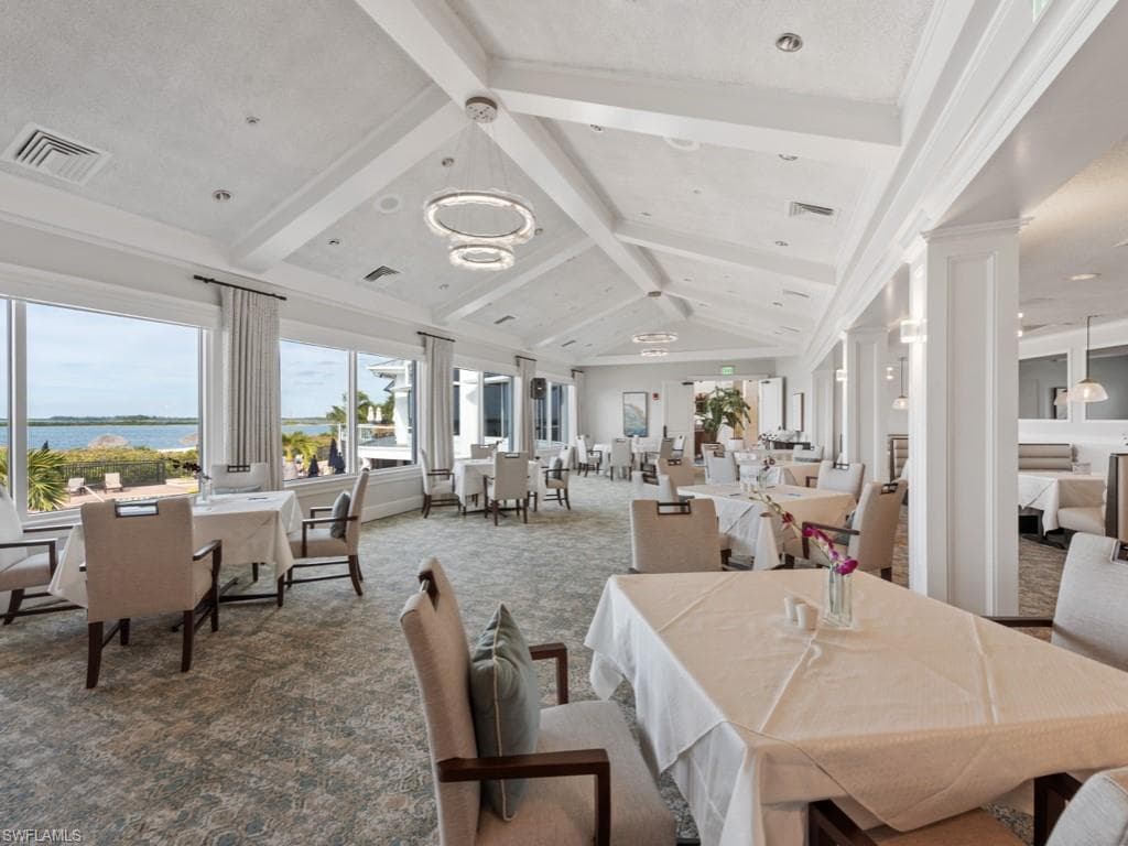 Dining space featuring carpet flooring, plenty of natural light, a water view, and ornate columns
