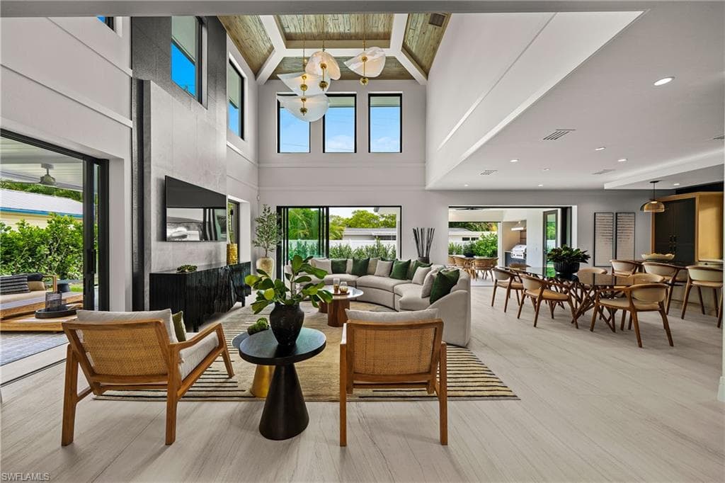 Living room featuring high vaulted ceiling, beamed ceiling, light wood finished floors, and a fireplace