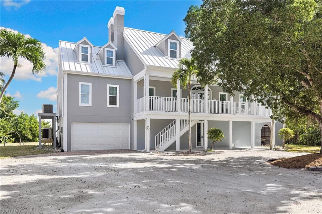 View of front facade with a chimney, an attached garage, driveway, stucco siding, and stairs