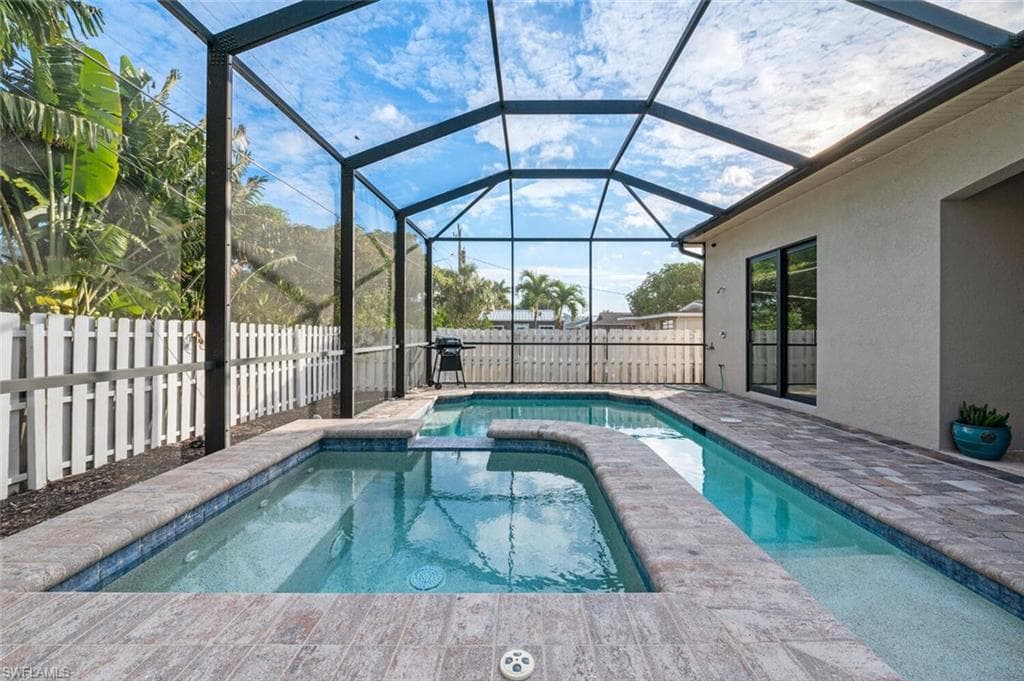 View of swimming pool featuring a pool with connected hot tub, a fenced backyard, a lanai, and a patio area