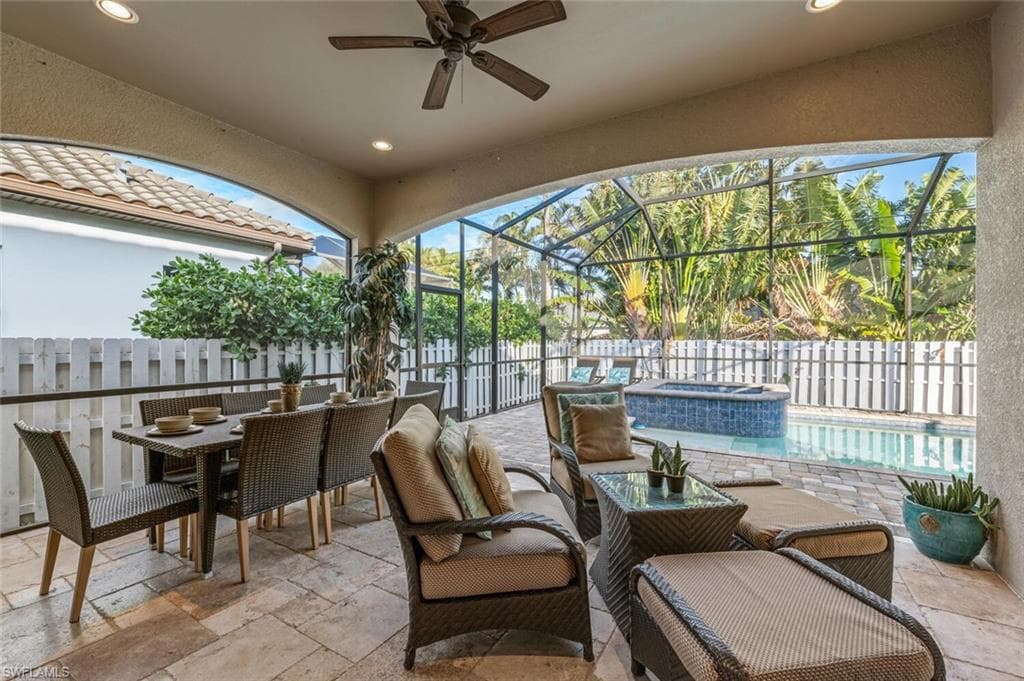 View of patio / terrace featuring a ceiling fan, a lanai, a pool with connected hot tub, and outdoor dining area