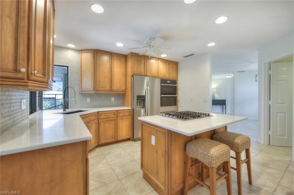 Kitchen with appliances with stainless steel finishes, a ceiling fan, light countertops, recessed lighting, and light tile patterned flooring