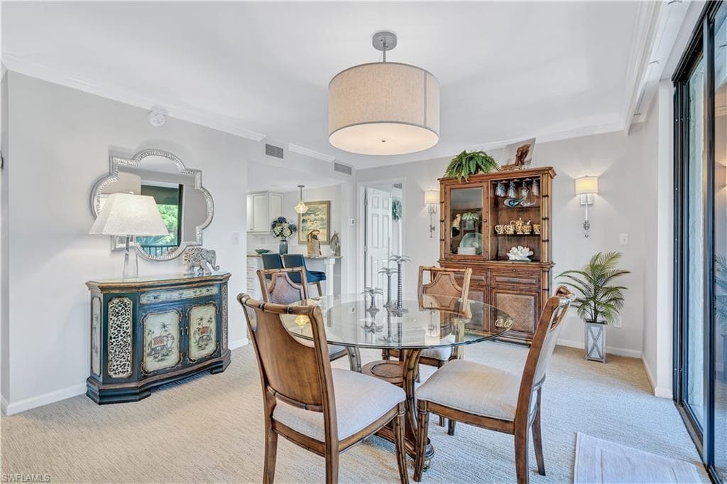 Dining area featuring light carpet and ornamental molding