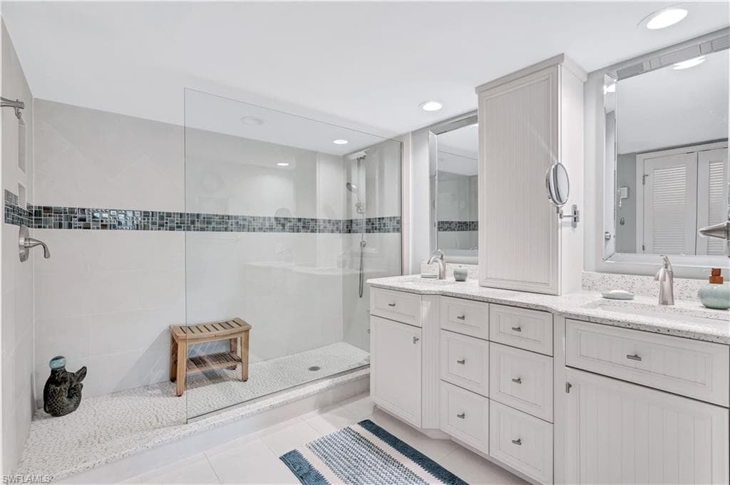 Newly refinished Primary Bathroom featuring tiled shower, double vanity, tile patterned flooring, and recessed lighting.