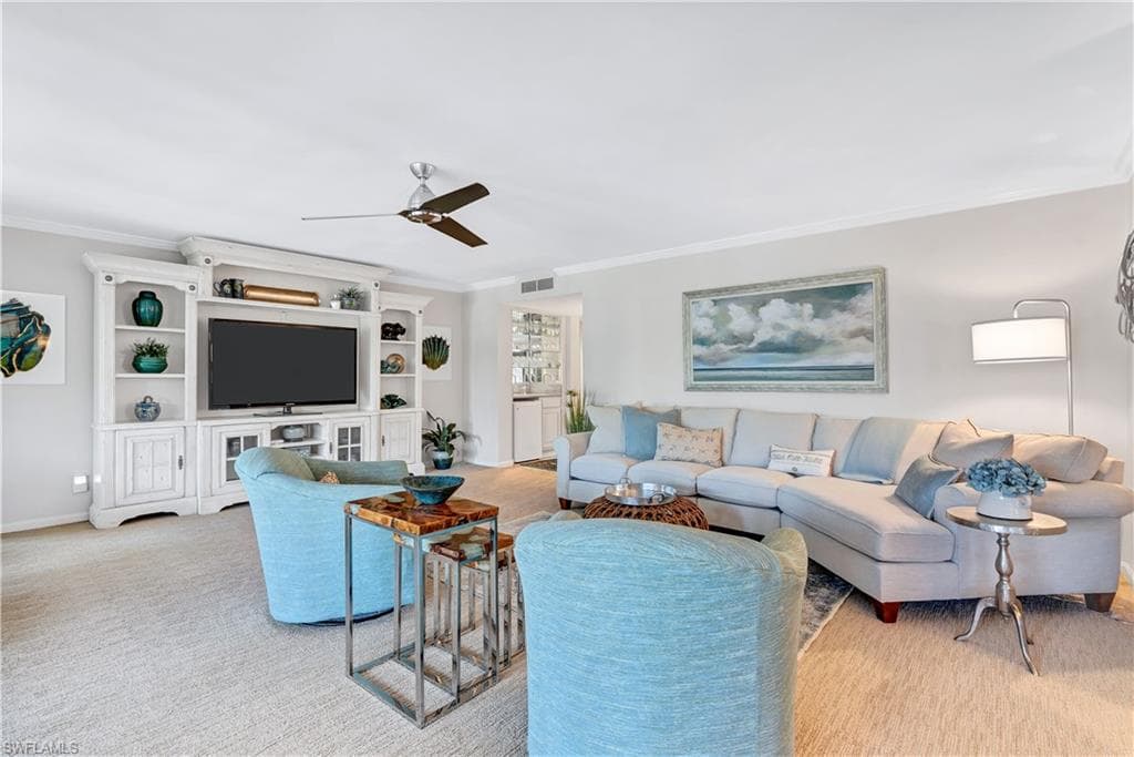 Living area featuring crown molding, ceiling fan, and carpet