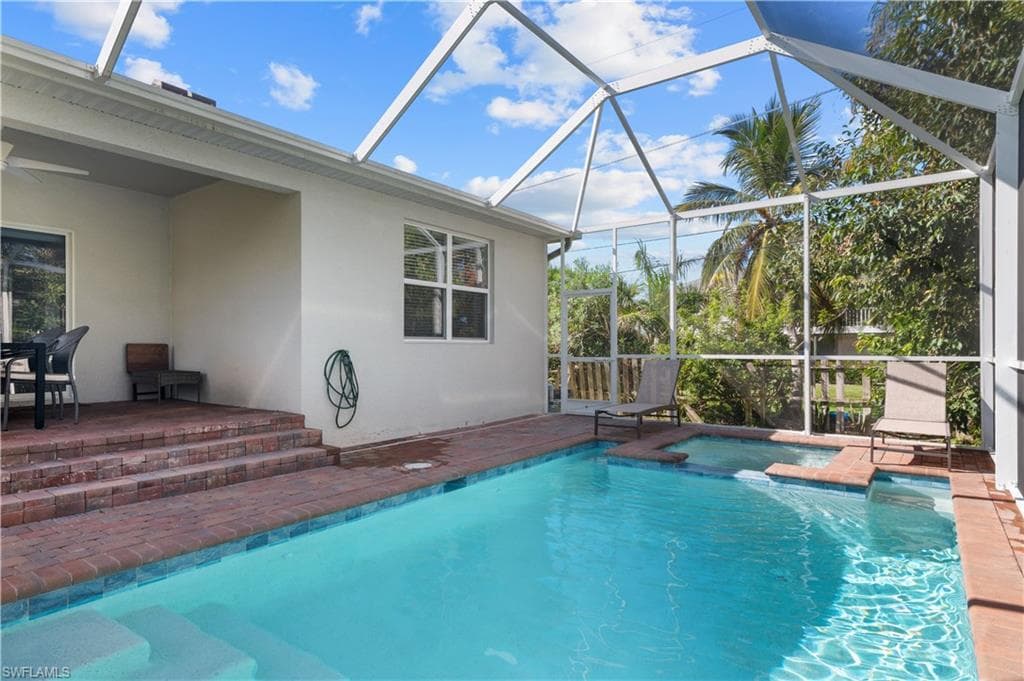 View of pool with a patio, glass enclosure, a pool with connected hot tub, and ceiling fan