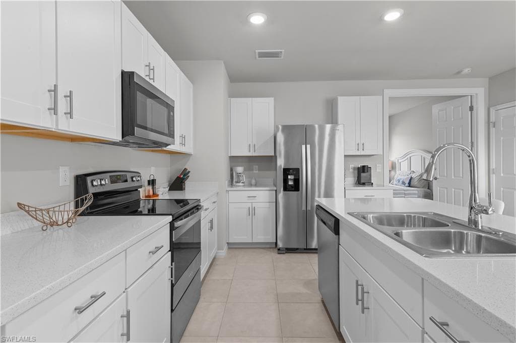 Kitchen featuring stainless steel appliances, white cabinetry, recessed lighting, light tile patterned floors, and light stone countertops