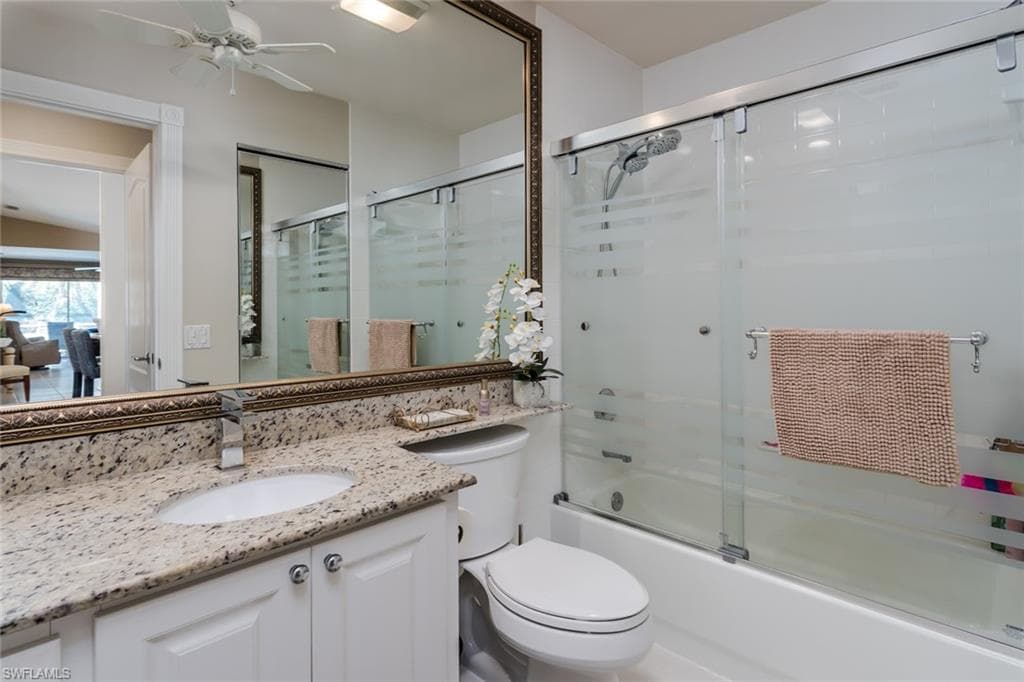 Full bath featuring shower / bath combination with glass door, vanity, and ceiling fan