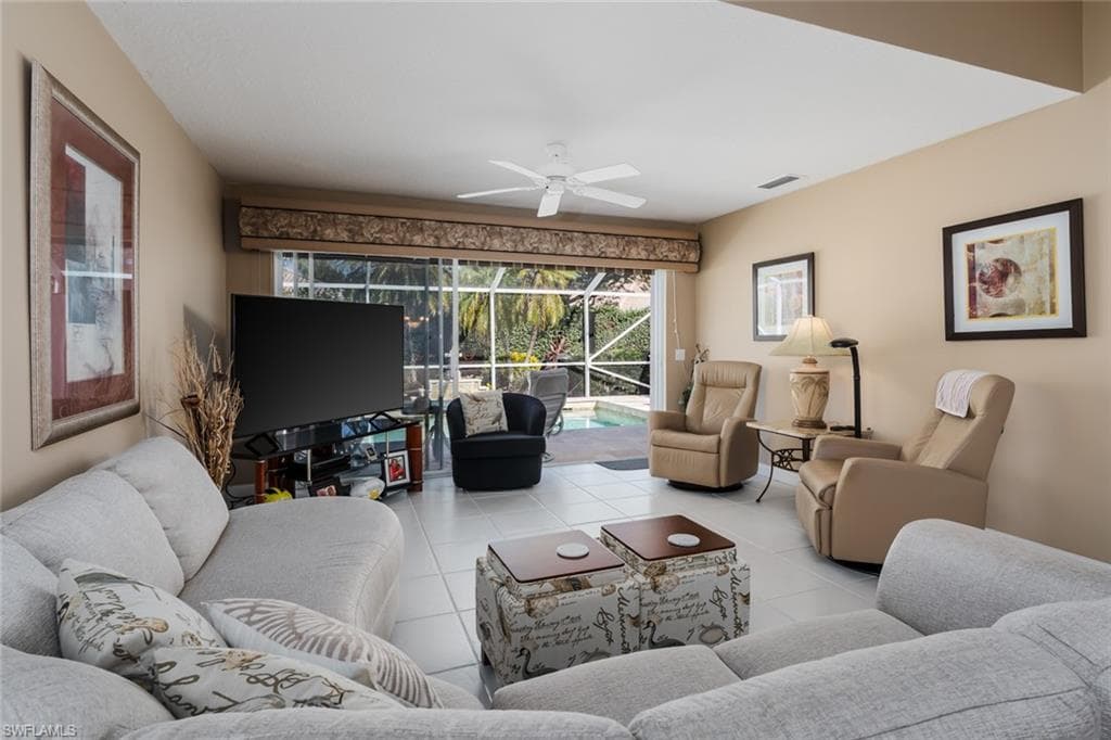 Living area with light tile patterned flooring, ceiling fan, and a sunroom