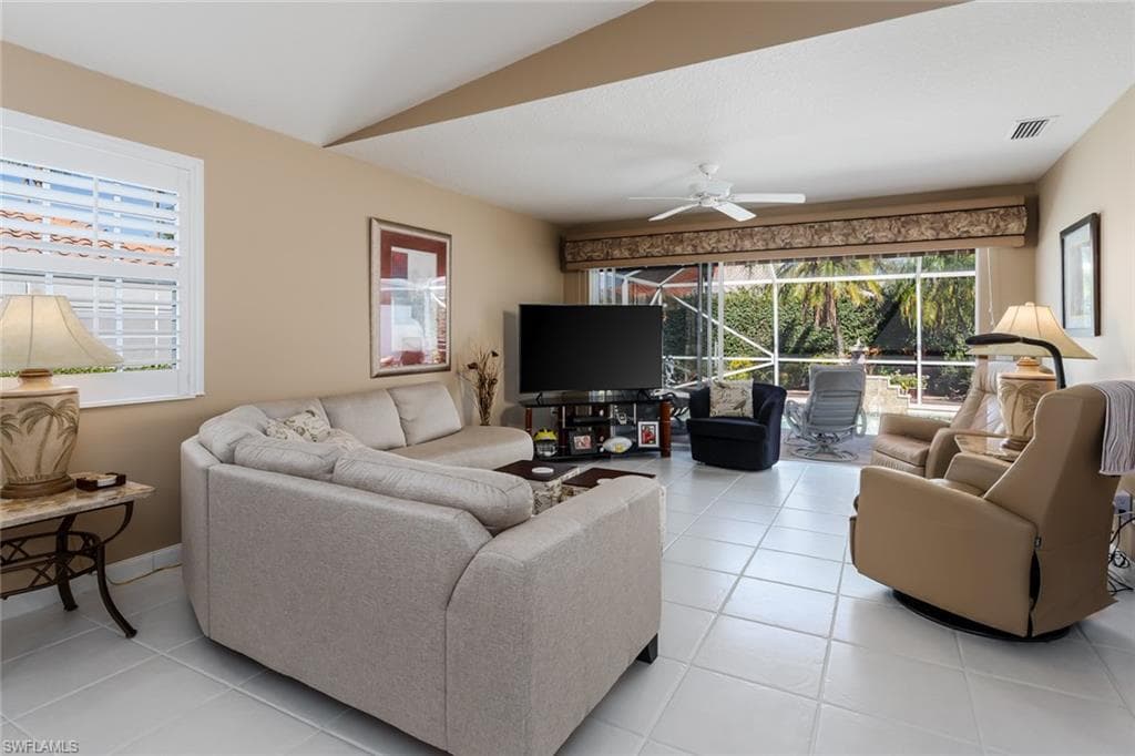 Living area featuring healthy amount of natural light, light tile patterned flooring, vaulted ceiling, and ceiling fan