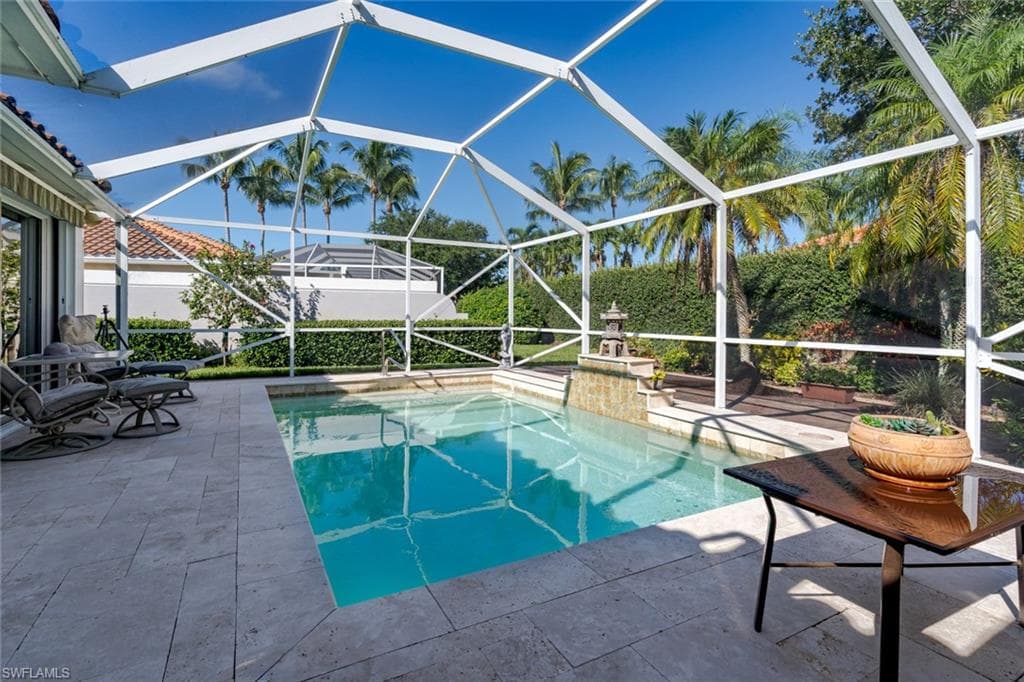 Outdoor pool with a sunroom, glass enclosure, and a patio
