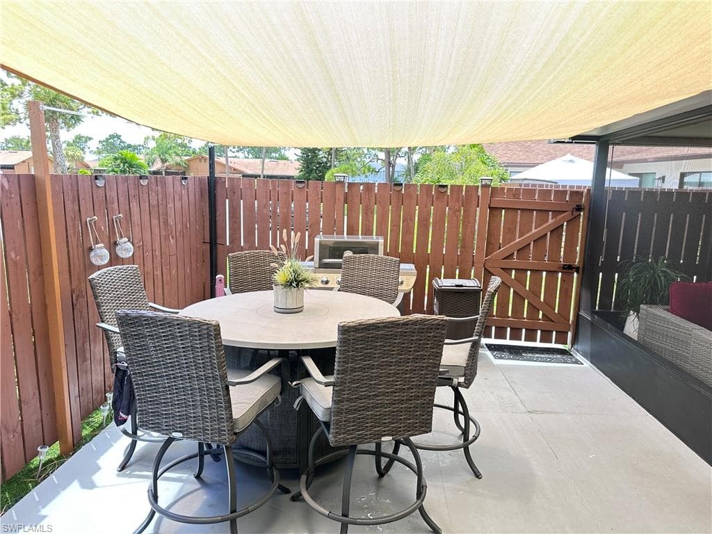 View of patio featuring outdoor dining space and a gate