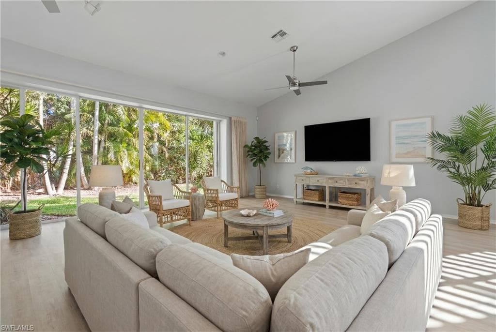 Living area with wood finished floors, a ceiling fan, and high vaulted ceiling
