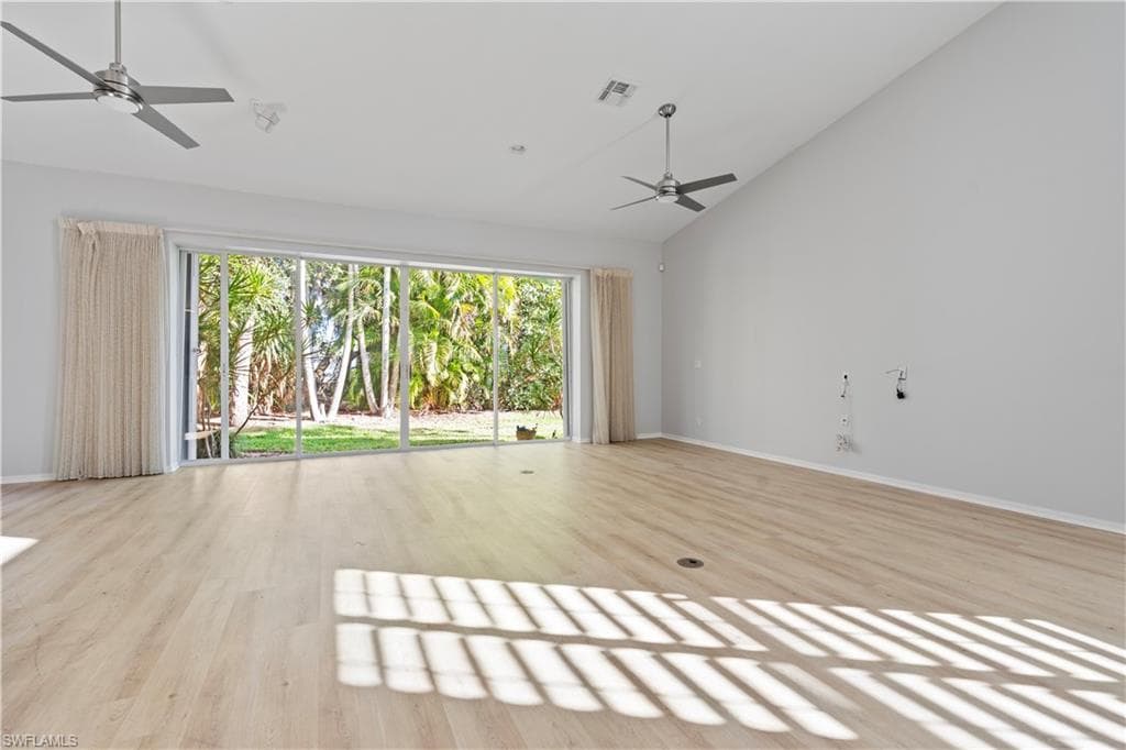 Unfurnished living room with a ceiling fan, light wood-type flooring, and high vaulted ceiling