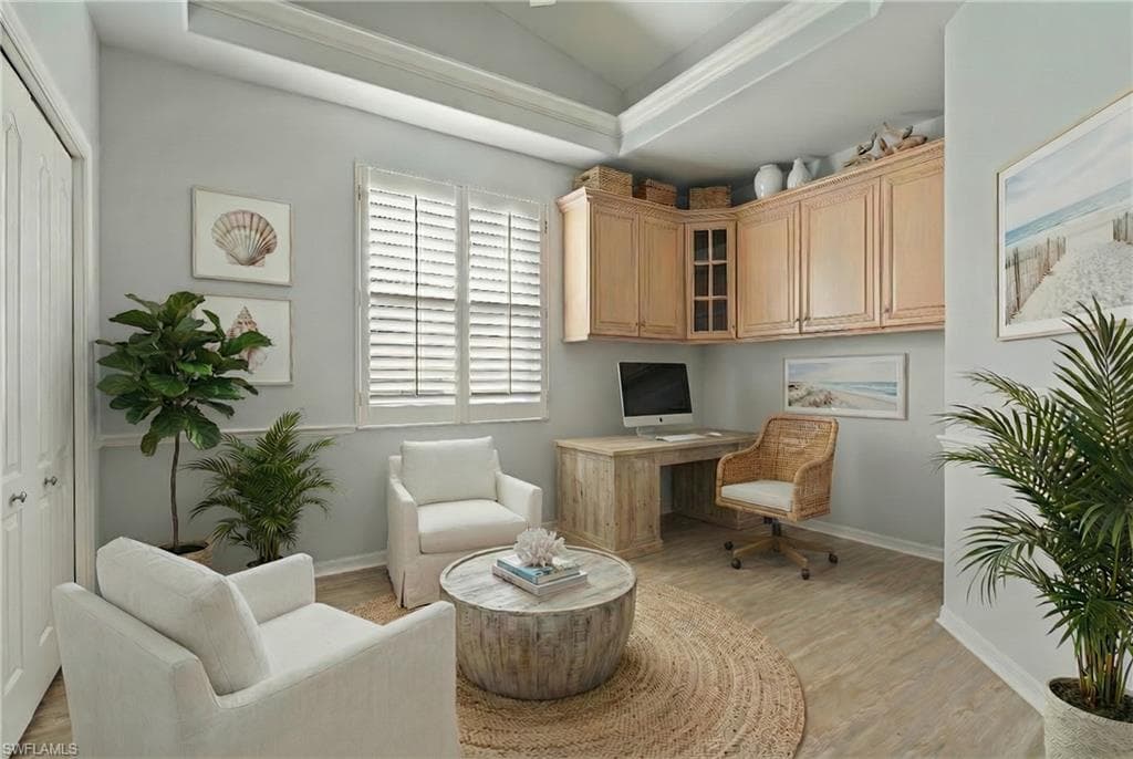 Home office featuring vaulted ceiling, built in desk, and light wood-style floors